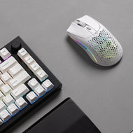 A top-down view of a Model O 2 Wireless in White on top a grey mousepad. A GMMK PRO 75% and black wooden wrist rest are partially visible on the side.